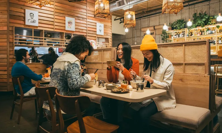 friends enjoy large bowls of Thai fare in a warmly lit restaurant