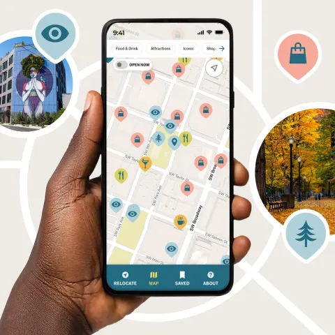 A hand holds up a phone displaying the Near Me Now app, which shows a map with colorful icons for shopping, nature, food and other similar locations